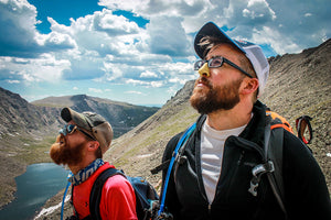 Two men on a hike in the mountains wearing colorful reef safe sunscreen on their nose